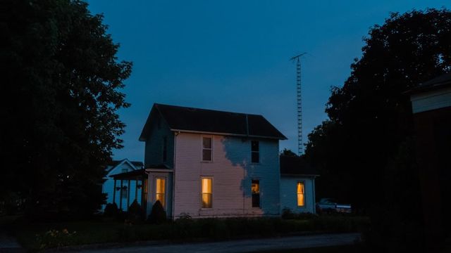 A house lit up at night with the interior lights on, seen from outside.