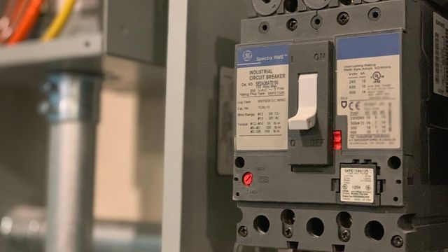 Close-up of a gray electrical power switch box with its handle visible.
