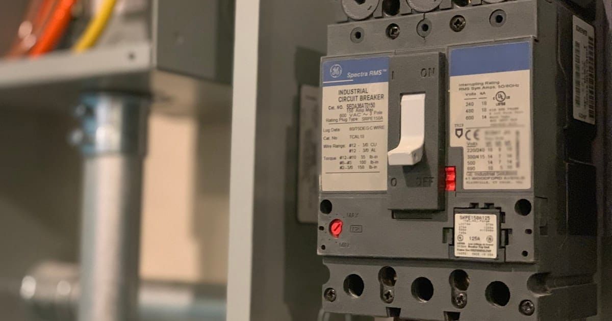 Close-up of a gray electrical power switch box with its handle visible.