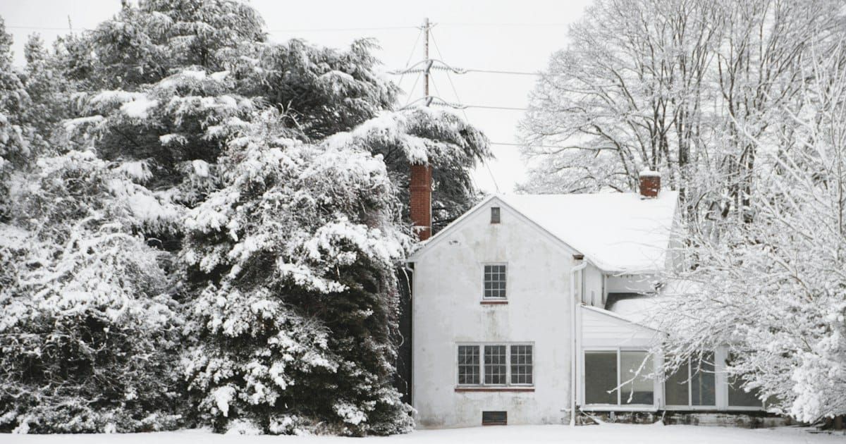 A white house and snow covered trees under power lines after a winter storm.