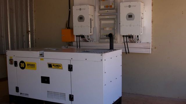 A white standby generator unit installed beside wall-mounted power equipment.